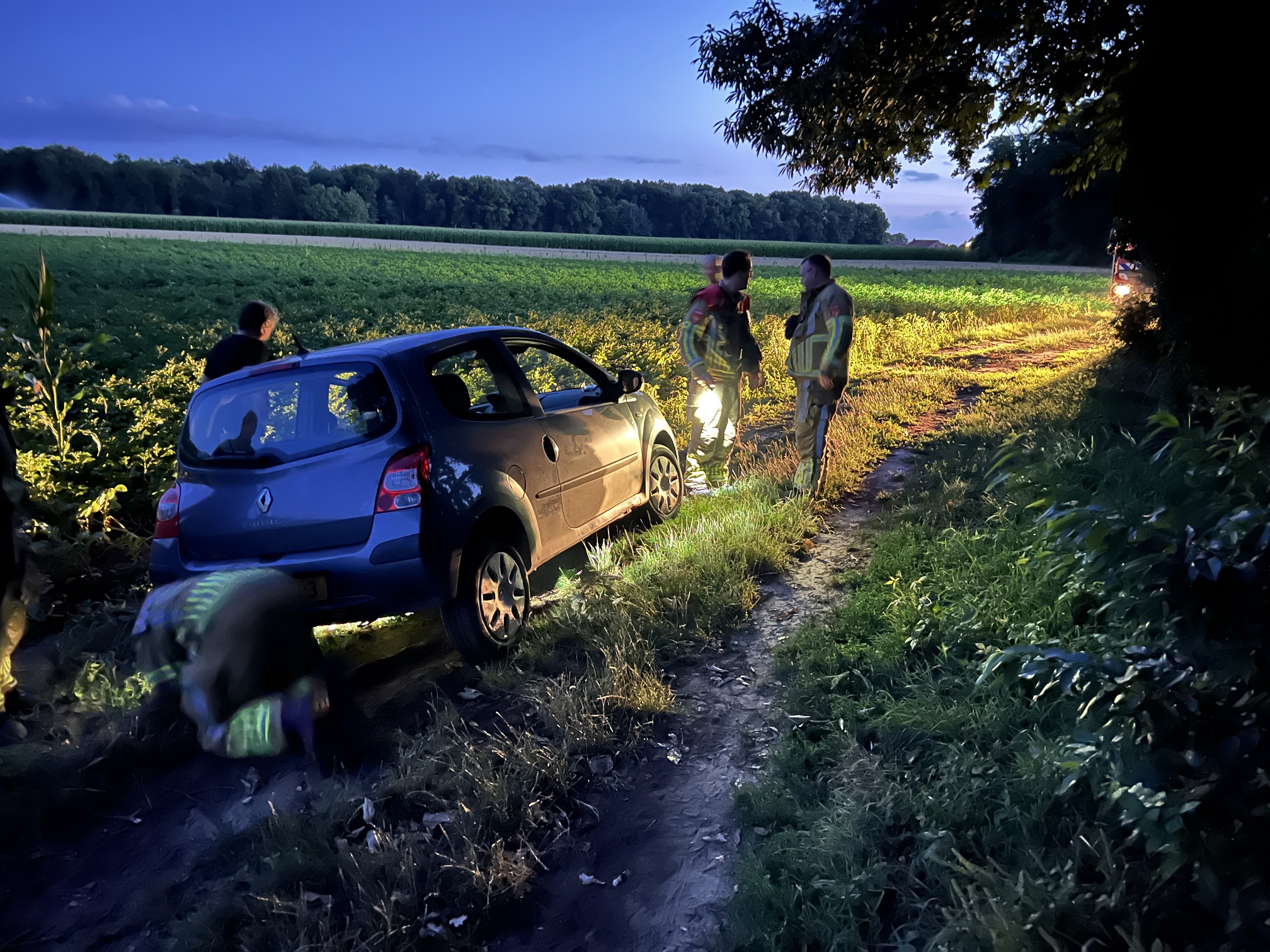 Brandweer helpt auto uit weiland